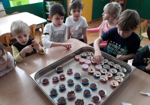 Dzieci układają foremki z ciastem na brytfannie