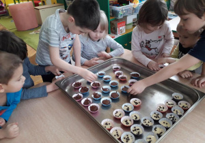 Dzieci układają foremki z ciastem na brytfannie