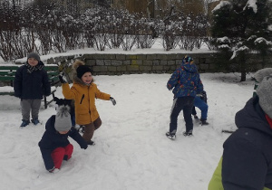 Dzieci biegają i rzucają się śnieżkami.