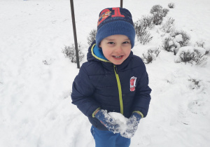 Chłopiec trzyma w rękach śnieżkę.