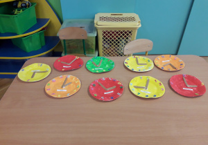 Na stoliku leżą zrobione przez dzieci zegary.