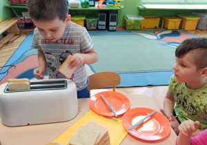 Chłopiec wkłada chleb do tostera
