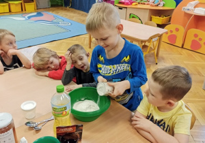 Chłopiec wsypuje mąkę do miski