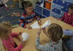 Dzieci składają kartki w rożki.