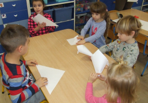 Dzieci składają kartki w rożki.