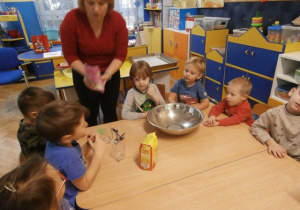 Nauczycielka pokazuje składniki do wykonania ciastek.