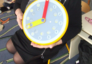 Nauczycielka prezentuje zegar do nauki odmierzania czasu.