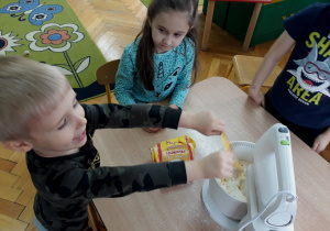 Dzieci robią ciasto za pomocą miksera