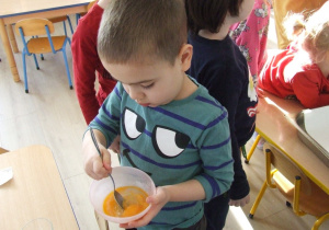 Chłopiec miesza jajko w misce.