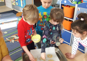 Dzieci posypują ciasteczka dodatkami.