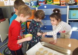 Dzieci posypują ciasteczka dodatkami.