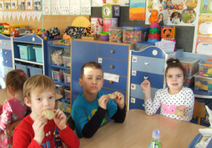 Dzieci jedzą upieczone ciasteczka.