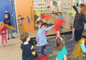 Dzieci tańczą z chustami w rytm muzyki.