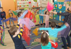 Dzieci tańczą z chustami w rytm muzyki.