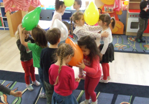 Dzieci tańczą w parach z balonikiem między głowami.