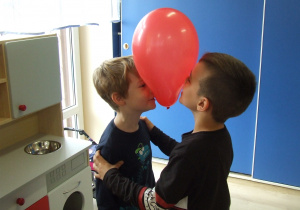 Dzieci tańczą w parach z balonikiem między głowami.