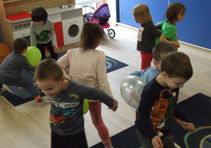Dzieci tańczą w parach z balonikiem między plecami.
