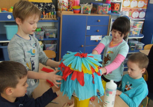 Dzieci przyklejają bibułę na balon.