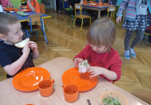 Dzieci jedzą kanapki z kiełkami.