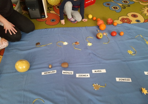Dzieci dobieraja owoce i układają owocowy Układ Słoneczny.