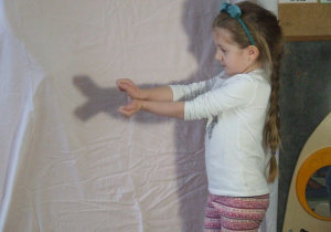 Dziewczynka tworzy cień z rąk.