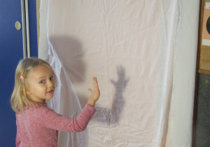 Dziewczynka tworzy cień z rąk.