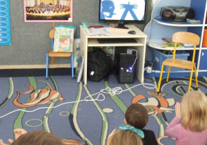 Dzieci oglądają teatrzyk cieni na komputerze.