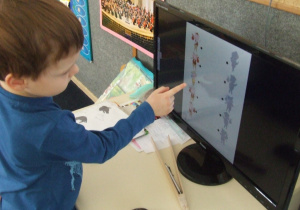 Chłopiec pokazuje obrazek i jego cień na komputerze.