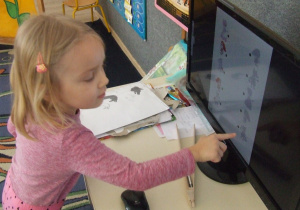 Dziewczynka pokazuje obrazek i jego cień na komputerze.