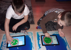 Dzieci grają w grę edukacyjną na tablecie.