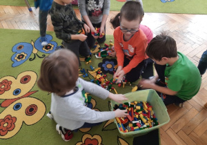 Dzieci wspólnie sprzątają zabawki.