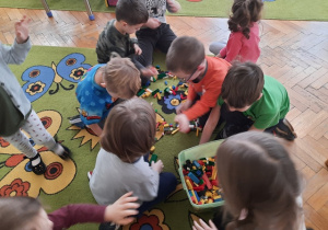 Dzieci wspólnie sprzątają zabawki.