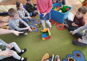 Dzieci wspólnie budują dom z klocków.