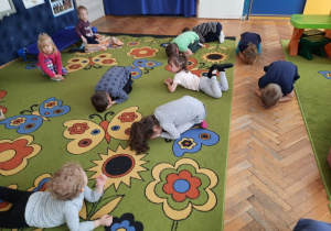 Dzieci leżą na dywanie, udając śpiące nasionka.