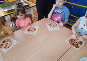 Dzieci posypują pizzę serem .