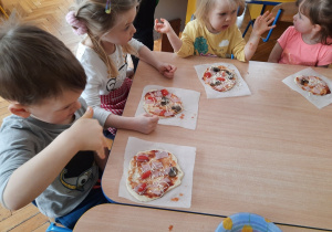 Dzieci posypują pizzę serem .