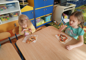 Dzieci jedzą pizze.