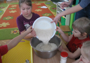 Dzieci wlewają zaczyn do mąki.