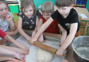 Dzieci wałkują ciasto na pizze.