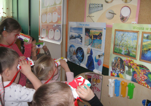 Dzieci obserwują przez lornetki obrazy.