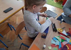 Dziewczynka wykleja pudełko papierem kolorowym.