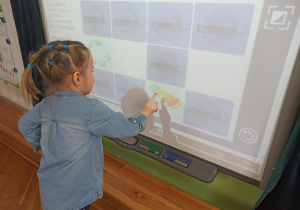 Dziewczynka odkrywa instrumenty na tablicy multimedialnej
