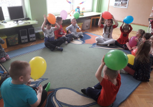 Dzieci pocierają balon o swoje włosy.
