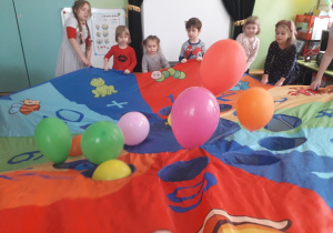 Dzieci bawią się balonami i chustą animacyjną.