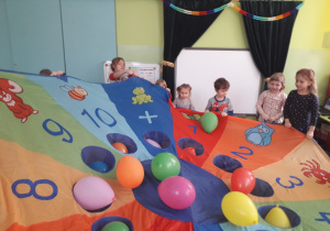 Dzieci bawią się balonami i chustą animacyjną.