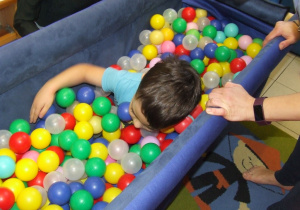 Chłopiec w basenie z piłkami wyszukuje ukryte skarby.