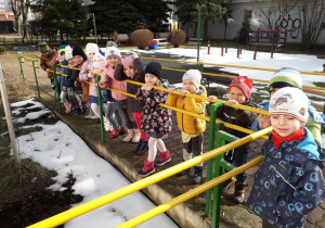Dzieci stoją przy barierce w ogrodzie