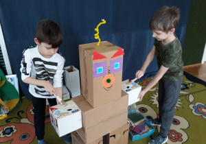 Dzieci smarują klejem elementy robota