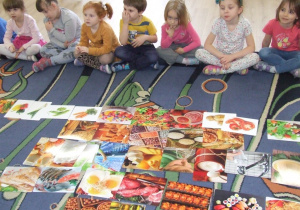 Dzieci oglądają gotową obrazkową piramidę żywieniową.