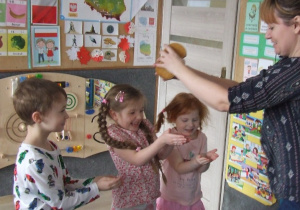 Nauczycielka kropi wodą ręce dzieci.